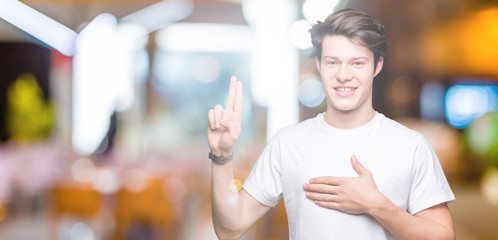 Young handsome man wearing casual white t-shirt over isolated background Swearing with hand on...