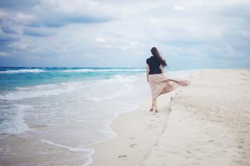 Fototapeta na wymiar young woman in a long skirt walking on the ocean. 