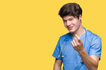 Young doctor wearing medical uniform over isolated background Beckoning come here gesture with hand inviting happy and smiling