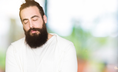 Fototapeta premium Young man with long hair and beard wearing sporty sweatshirt with hand on stomach because nausea, painful disease feeling unwell. Ache concept.