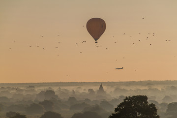 Balloon over Bagan, landing airplane and the skyline of its temples, Myanmar
