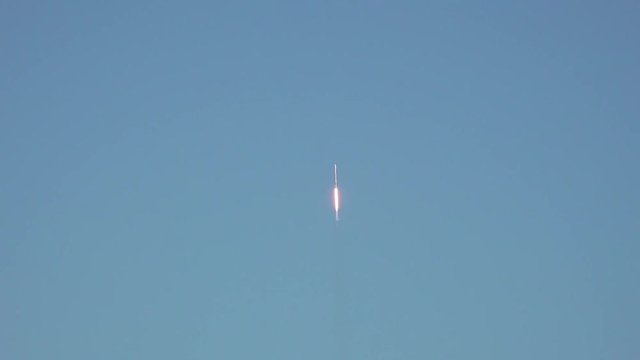 Commercial space rocket lifting-off into space with exhaust flames and smoke. Beautiful clouds and sky. Wide-angle.  120 fps slow motion.