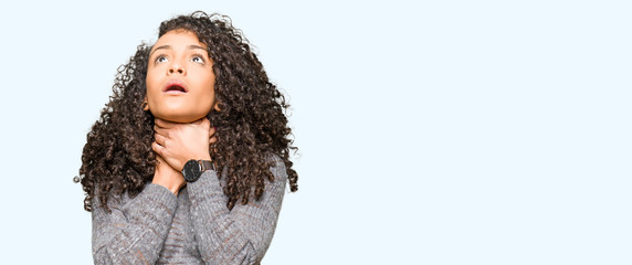Young beautiful woman with curly hair wearing grey sweater shouting and suffocate because painful...