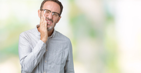 Naklejka na ściany i meble Handsome middle age elegant senior man wearing glasses over isolated background touching mouth with hand with painful expression because of toothache or dental illness on teeth. Dentist concept.