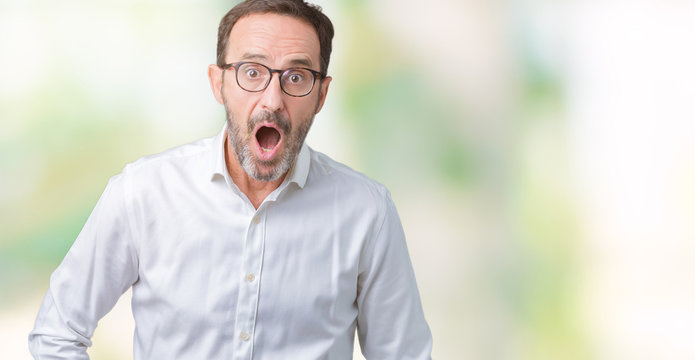 Handsome middle age elegant senior business man wearing glasses over isolated background afraid and shocked with surprise expression, fear and excited face.