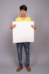 Young Asian teenage boy against gray background