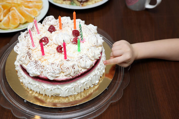 Dłoń dziecka dotyka palcem tort urodzinowy. - obrazy, fototapety, plakaty