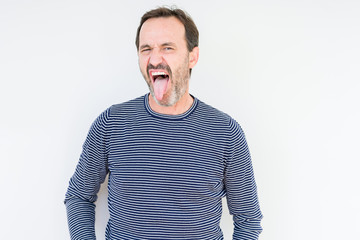 Obraz premium Handsome senior man over isolated background sticking tongue out happy with funny expression. Emotion concept.