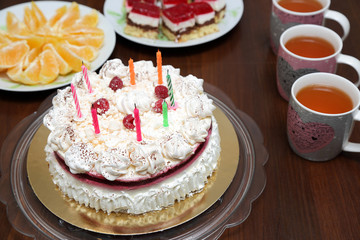 Tort urodzinowy i kubki z herbatą na stole.