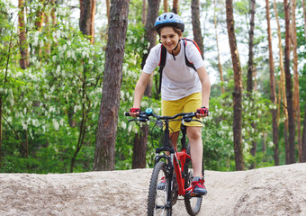 Child teenager on  bicycle ride in  forest at spring or summer. Happy smiling Boy cycling outdoors...