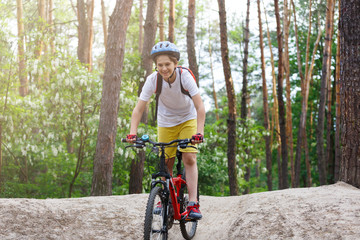 Naklejka premium Child teenager in white t shirt and yellow shorts on bicycle ride in forest at spring or summer. Happy smiling Boy cycling outdoors. Active lifestyle, hobby