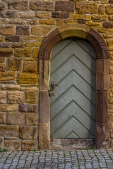 Fototapeta na wymiar historische Stadtmauer aus Sandstein mit Holztür und Türrahmen mit Rundbogen aus Sandstein gehauen mit besonderer Verriegelung