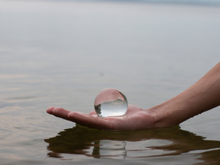 Fototapeta na wymiar hand holding a glass of water on the beach