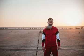 Portrait of handsome bearded mature man in sports suit, outdoors during sunset or sunrise