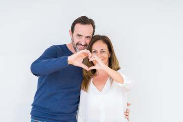 Beautiful middle age couple in love over isolated background Doing heart shape with hand and fingers smiling looking through sign