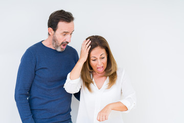 Beautiful middle age couple in love over isolated background Looking at the watch time worried, afraid of getting late