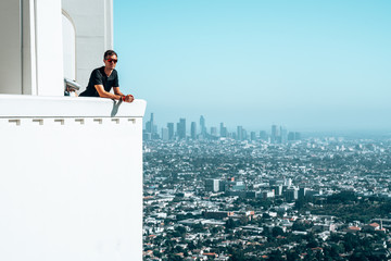 Young man sitting with a Los Angeles downtown view in the background. Amazing Hollywood.