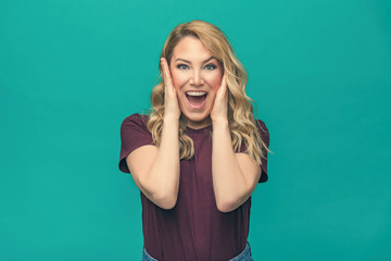 Fototapeta premium Portrait of blonde surprised emotional girl on blue background.