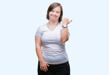 Young adult woman with down syndrome over isolated background smiling with happy face looking and pointing to the side with thumb up.