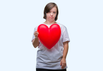 Young adult woman with down syndrome holding red heart over isolated background with a confident expression on smart face thinking serious