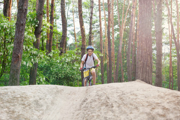 Obraz premium Child teenager on a bicycle ride in the forest at spring or summer. Boy cycling outdoors in helmet