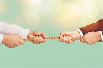 Business men hands holding rope on grey background