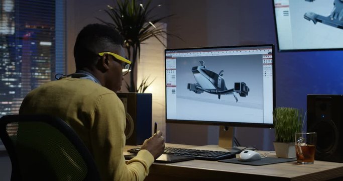 Medium shot of a young man sitting back and develops the design of spaceship 3D model for movie or video game