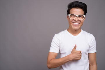 Portrait of young Asian man against gray background