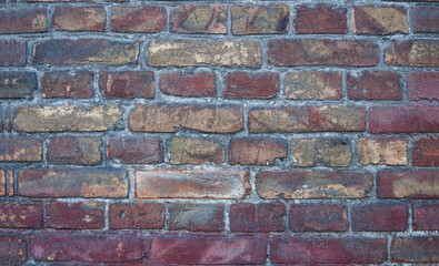 Fototapeta premium A wall of old, damaged red brick. Scratches and cracks. The background and texture of an antique retro brick.