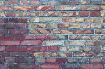 A wall of old, damaged red brick. Scratches and cracks. The background and texture of an antique retro brick.