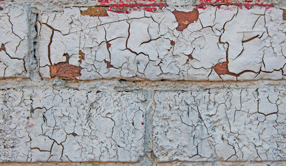 The texture of the old red brick, with cracked white paint. Close-up.