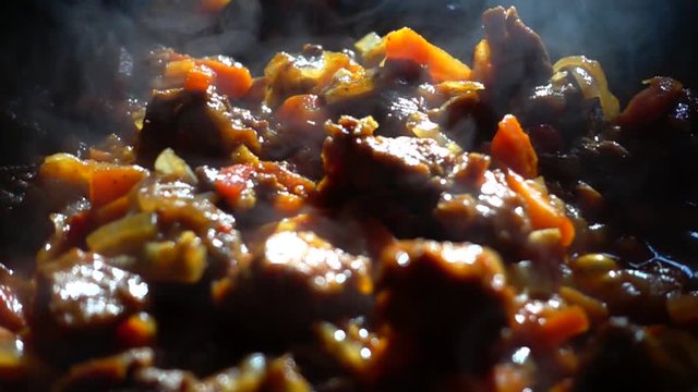 Process of preparation of goulash with vegetables in a pig-iron frying pan. Slow motion.