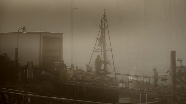 Lobster fishing boat unloading it&permil;&Ucirc;&ordf;s daily catch in early morning light at sunrise in a foggy and quaint New England harbor.