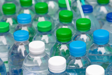 Many bottles of clean water with white blue and green lids and straws.