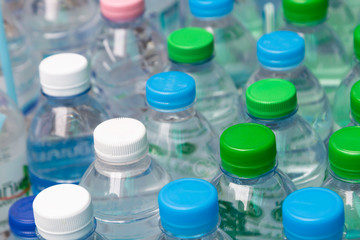 Many bottles of clean water with blue and green lids and straws.