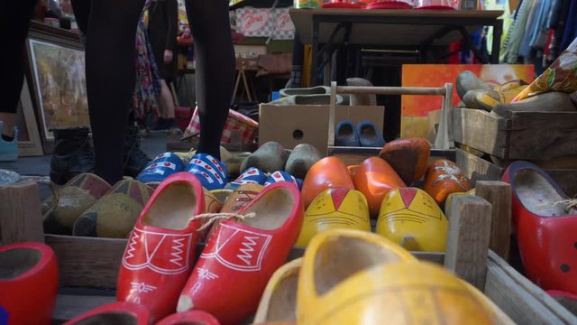 A girl trying out different kind of clogs, or "klompen" as they call them in Holland, traditional wooden footwear, at a market in Amsterdam.  In the style of the "Friesche" flag.