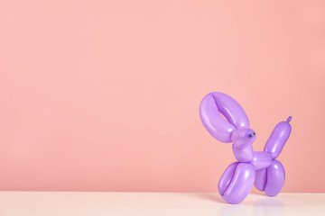 Animal figure made of modelling balloon on table against color background. Space for text
