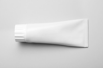 Blank tube of toothpaste on white background, top view