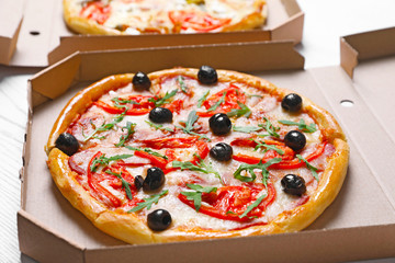 Cardboard boxes with tasty pizzas on table, closeup