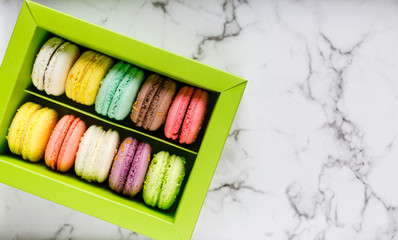 Green Box with colorful macarons on marble table background. Delicious  sweets
