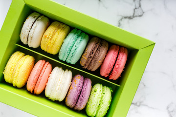 Green Box with colorful macarons on marble table background. Delicious  sweets