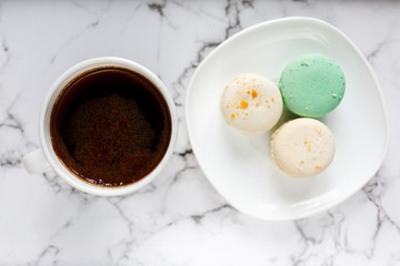 Fresh Coffee cup and plate with macarons on marble table background. Delicious coffee break with sweets