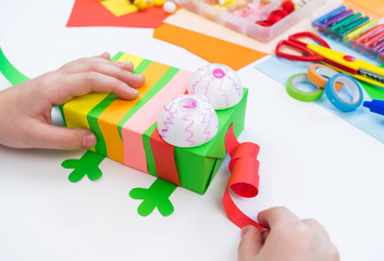 Child makes a hack box chameleon. Material for creativity on a white background.