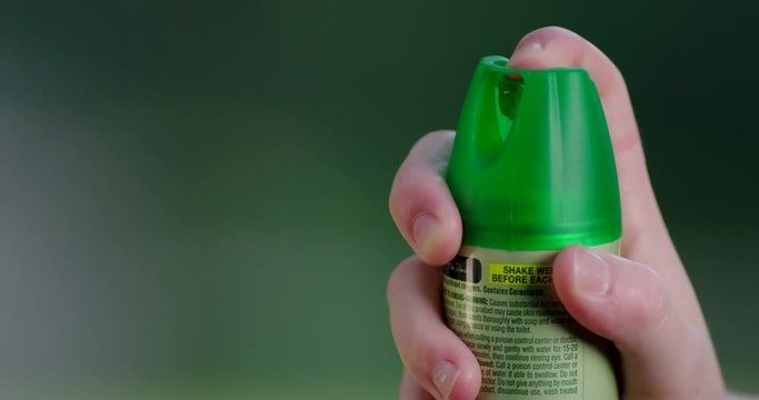 Close-up of hand spraying mosquito insect repellent aerosol can in slow motion