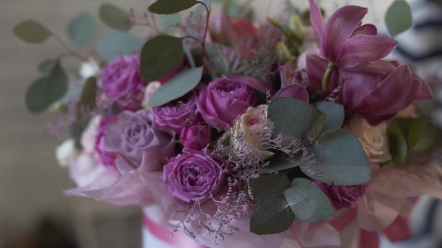 Slow shot of the bouquet in the foreground. Bouguet is very big and beautiful with purple and pink roses and many other greens.
