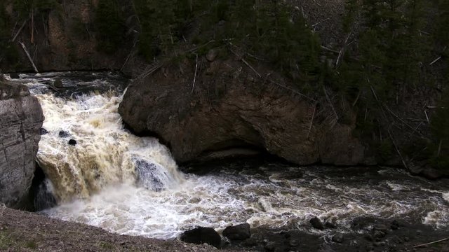 Firehole Falls in Yellowstone National park.  Massive amounts of water flow over the boulders and rocks. Wide shot.