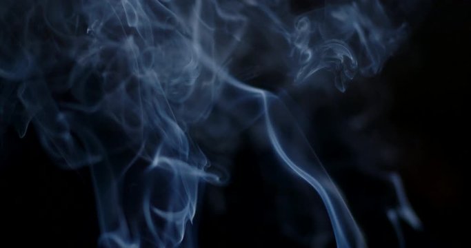 Bluish cloud of smoke or vapor rising against a black background in slow motion