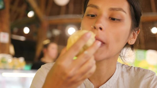 Young Mixed Race Tourist Girl Eating Fresh Ripe Durian. Happy Woman Enjoying Taste of Exotic Tropical Fruit. 4K. Kuala Lumpur, Malaysia.