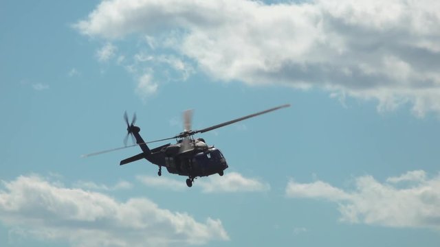 Military helicopter makes sharp turn and flies over the camera in slow-motion.  Blackhawk chopper. 