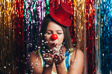 A female clown with colorful clothes and makeup on colorful background